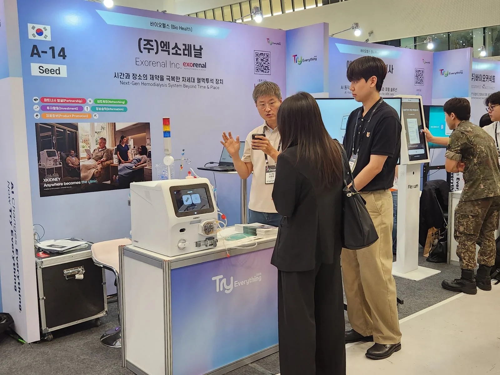 An Exorenal engineer explaining XKIDNEY to visitors at booth A-14